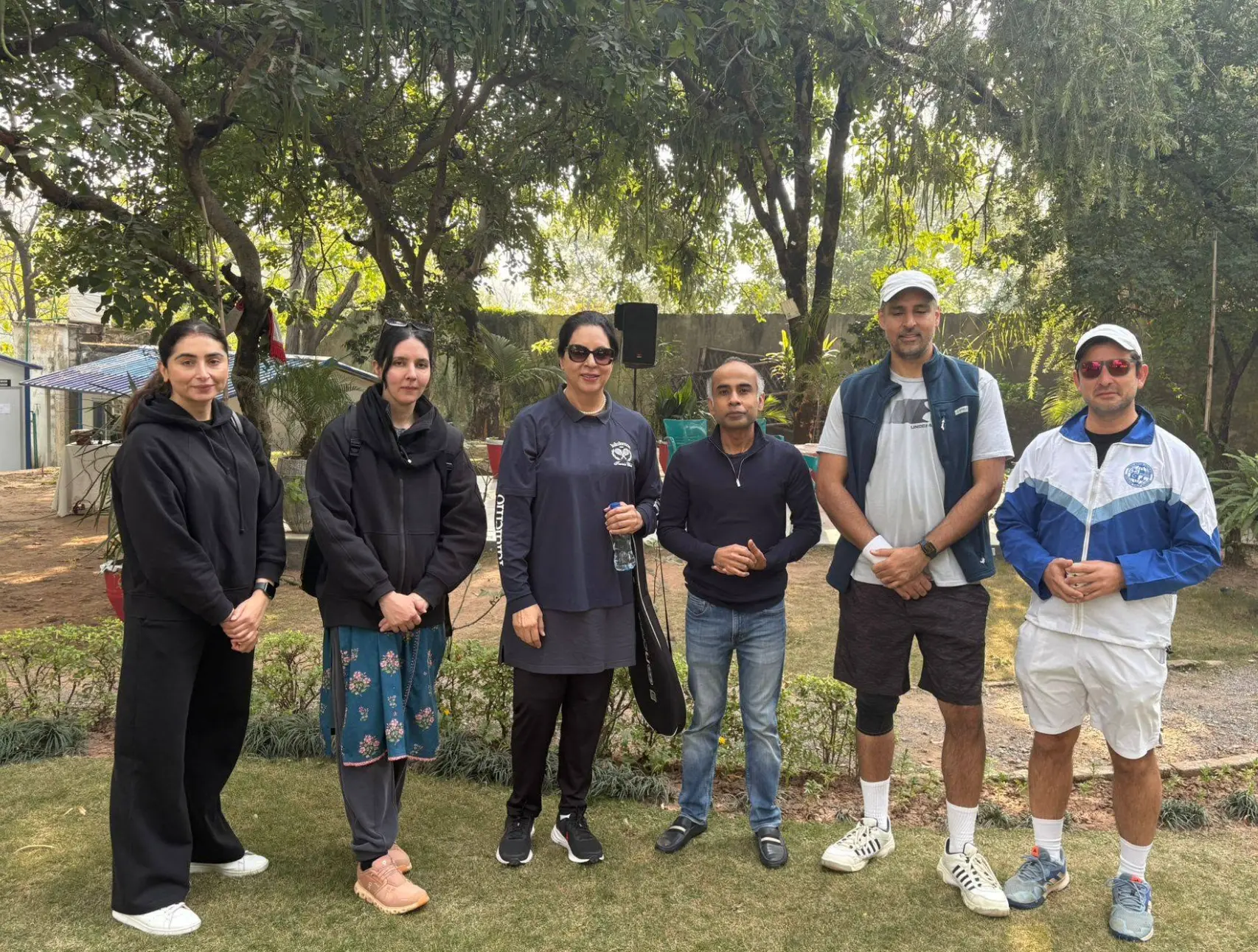 Group of club members standing together on the lawn in tennis kit